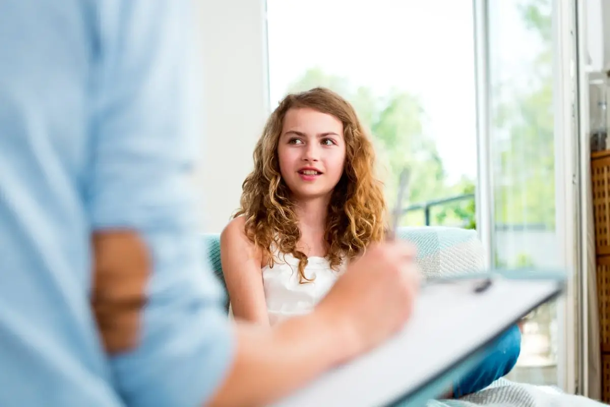 Teenage girl talking with therapist at home. Focus on background.